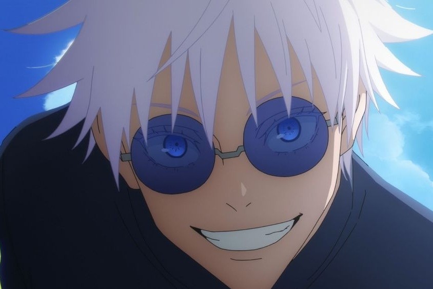 Satoru Gojo, pictured smiling and wearing a pair of blue sunglasses